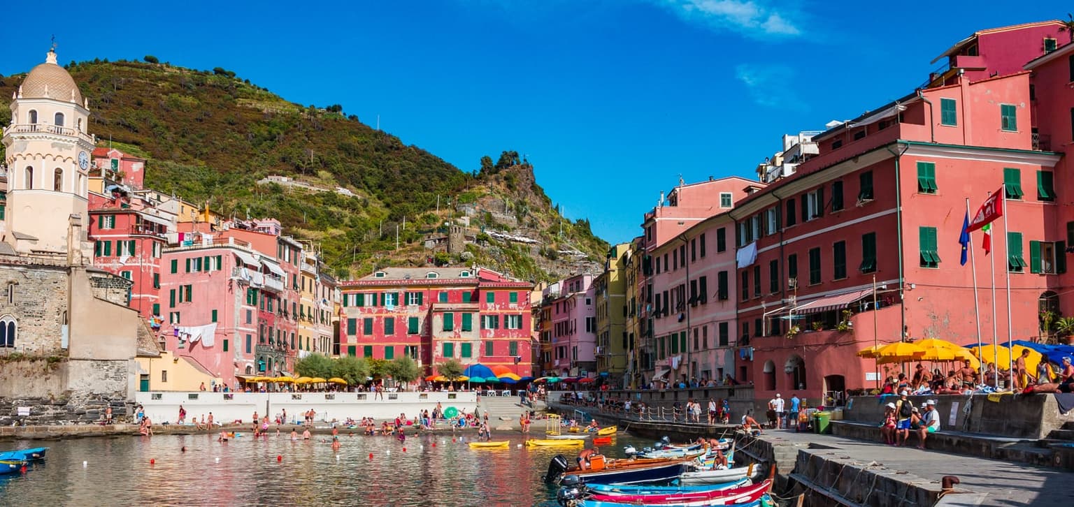 Vernazza's harbor and pastel houses seen from the water's edge, with fishing boats moored along the quay.