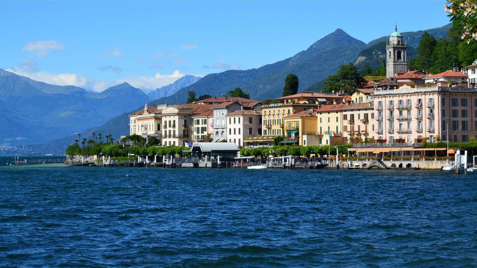 Bellagio's lakefront row of pastel hotels and the church bell tower seen from the water, mountains behind