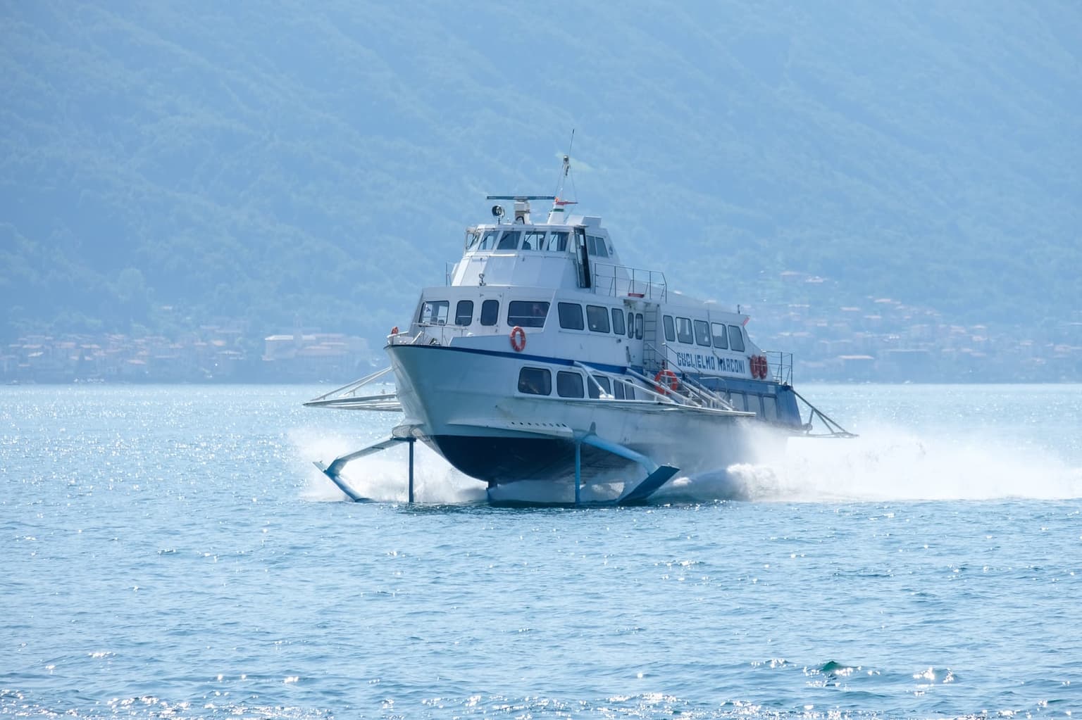 A Lake Como aliscafo hydrofoil skimming the lake up on its foils, throwing spray as it goes