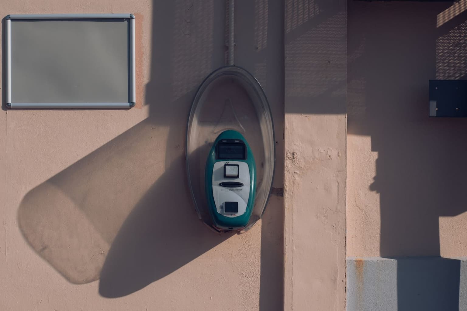 A teal Trenord ticket-validation machine on a station wall, the type you tap or stamp your regional ticket against before boarding