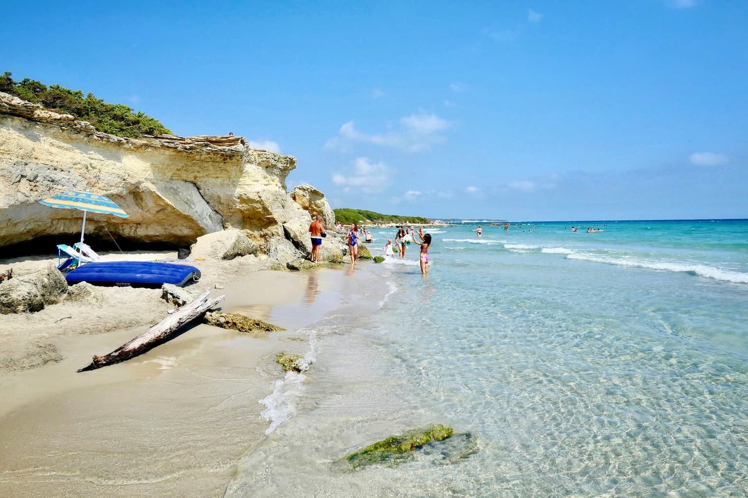 Pale sand and clear shallow water at Baia dei Turchi near Otranto, under a limestone overhang