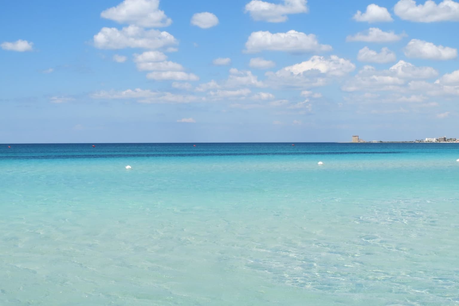 Very shallow, milky-turquoise water at Marina di Pescoluse, with a watchtower on the far shore