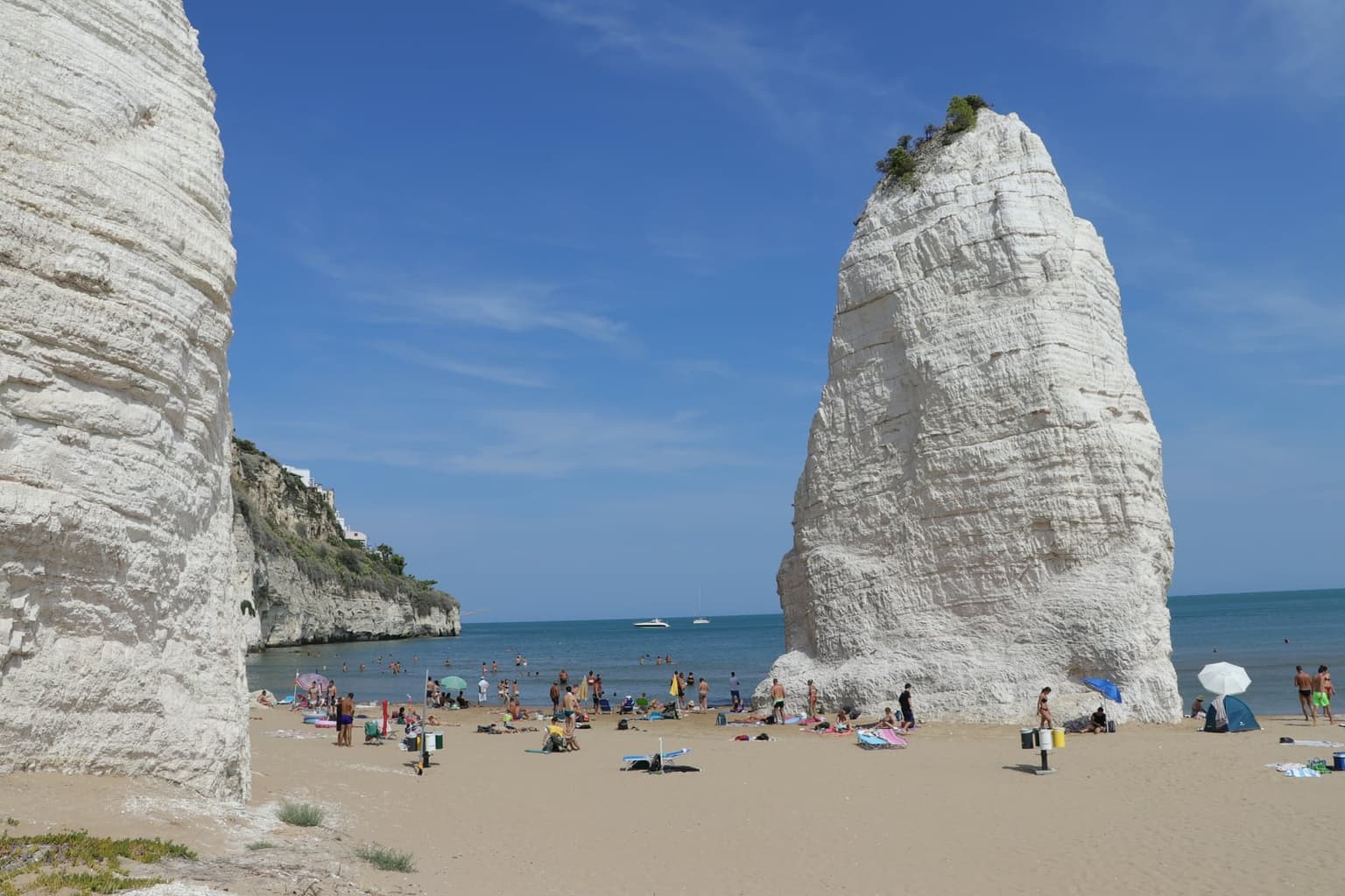 Pizzomunno, the white limestone monolith, on the beach at Vieste with swimmers in the water in front of it