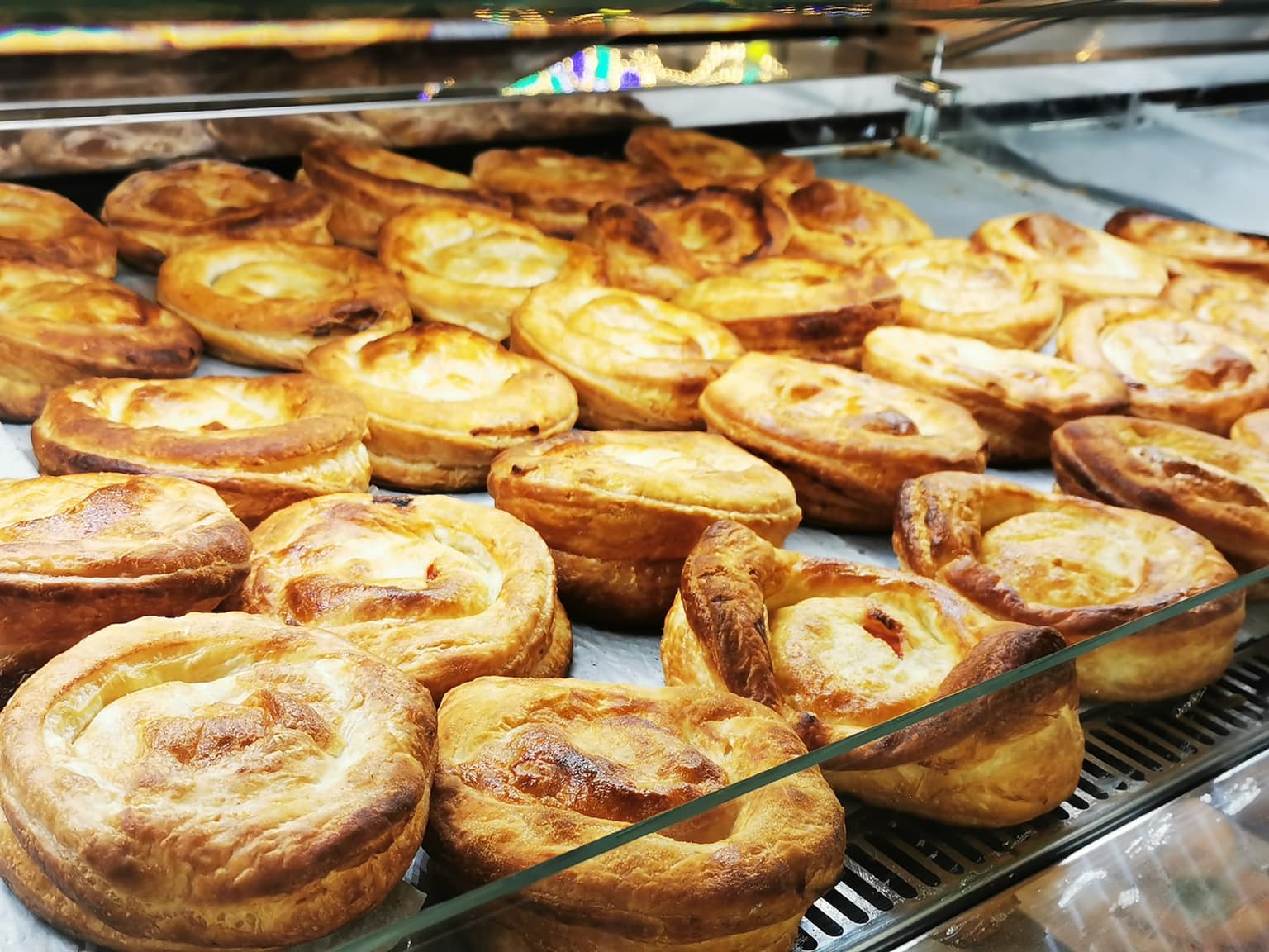 A tray of rustici, round puff pastries baked golden, crowded behind the glass of a display case