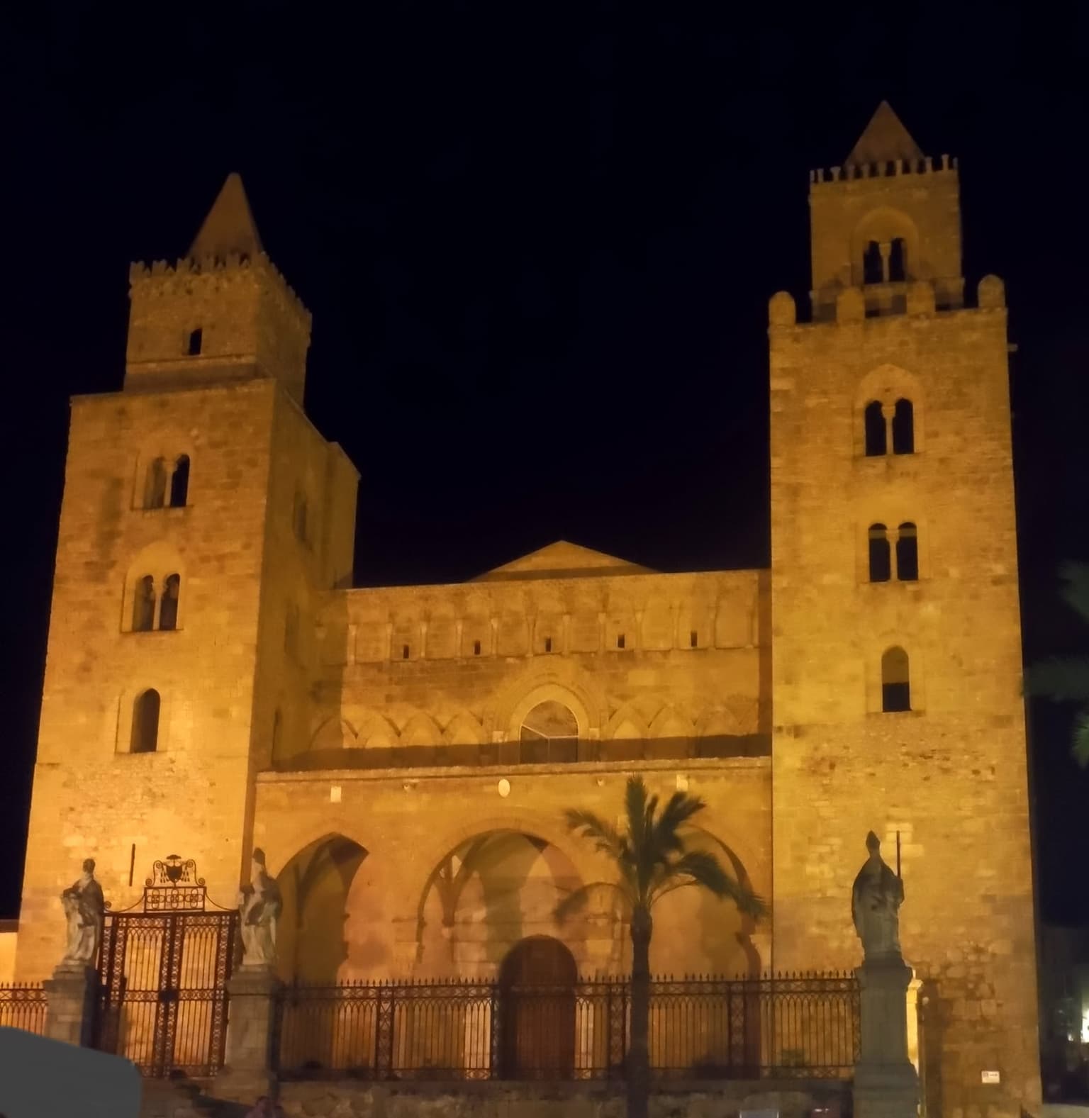 Cefalù cathedral's two towers and arched porch floodlit at night