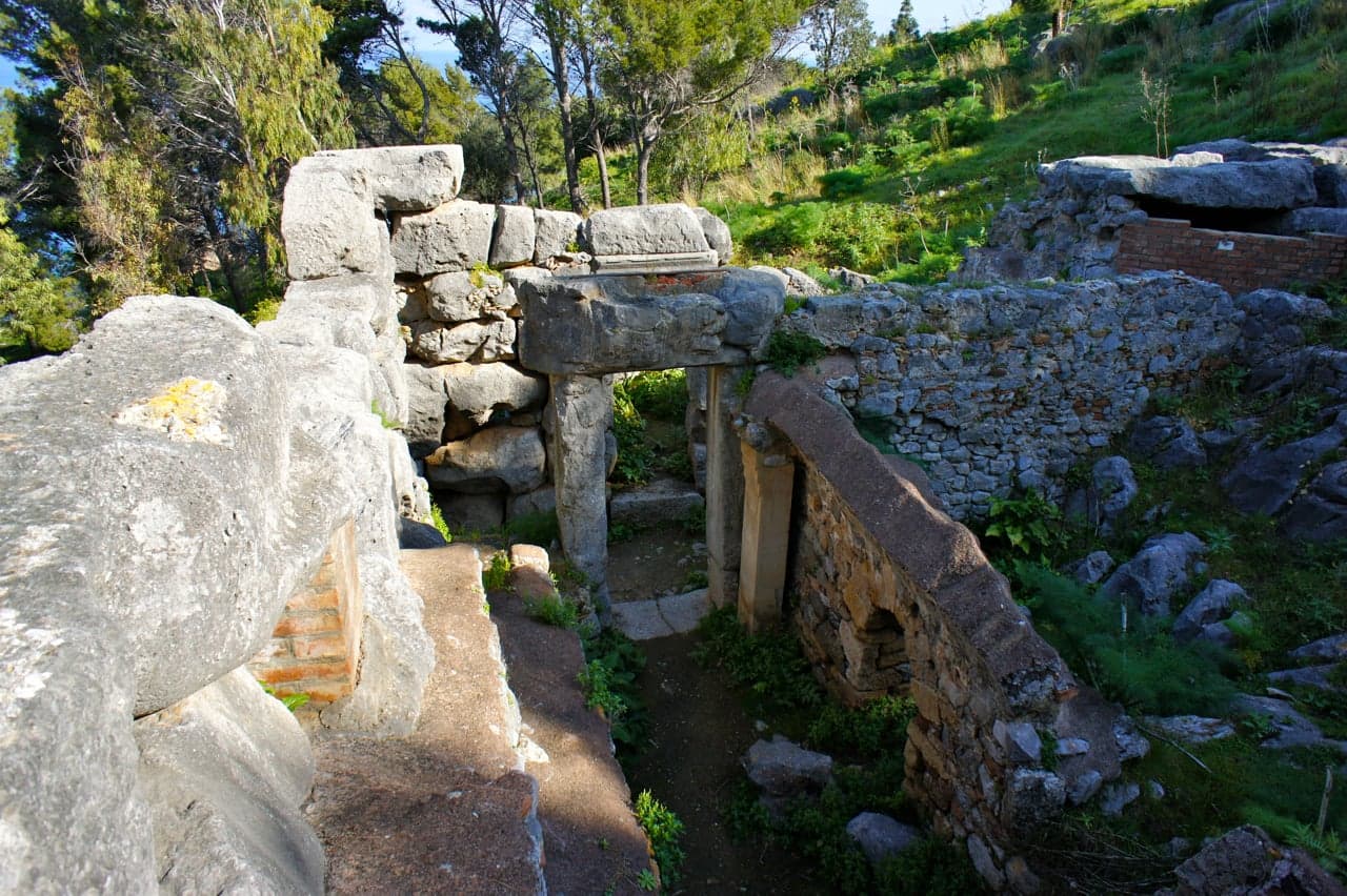 The megalithic Temple of Diana on La Rocca, a doorway of massive limestone blocks under a single stone lintel among the pines
