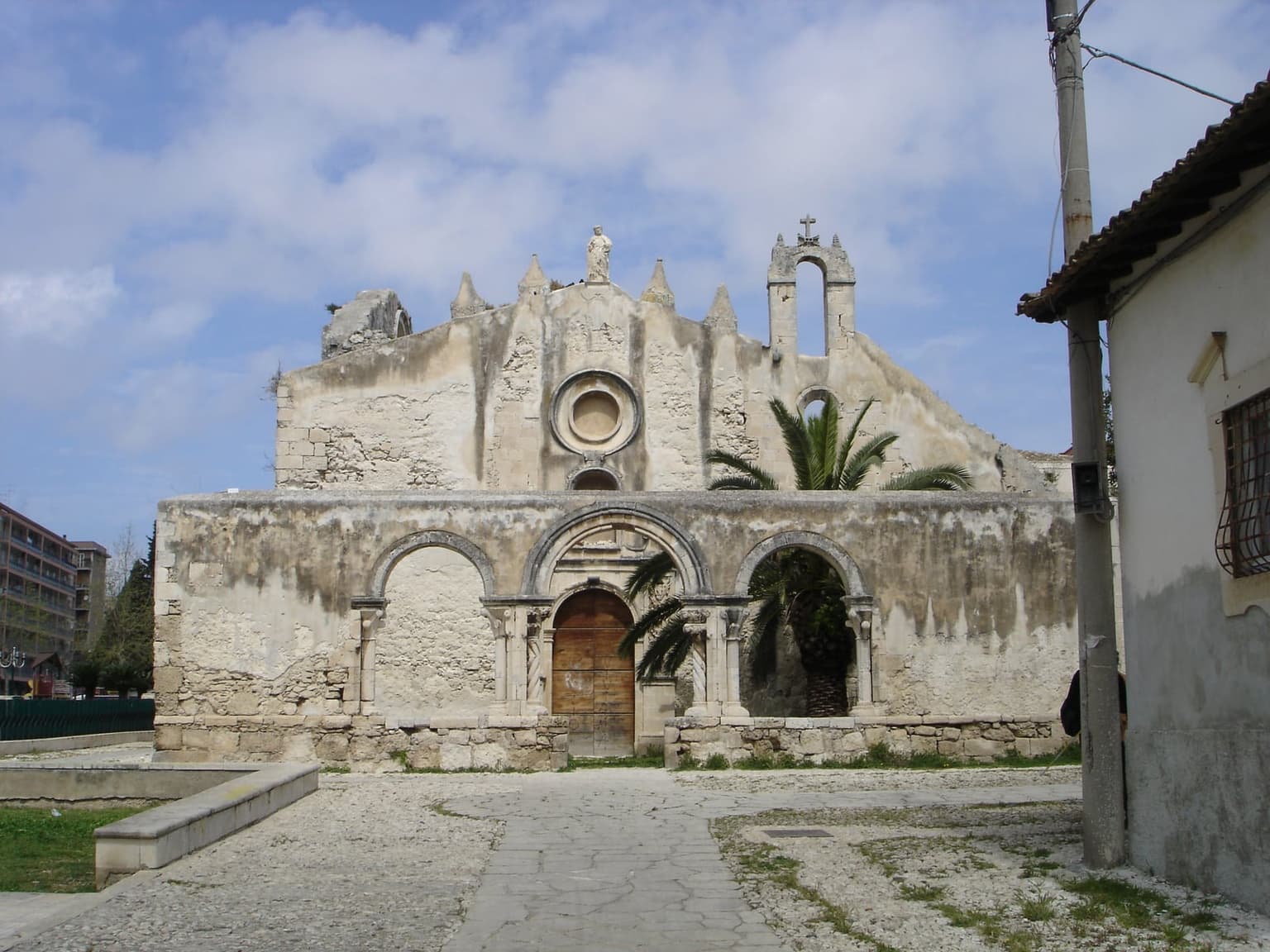 The ruined Norman-era basilica of San Giovanni, its roofless façade standing over the catacomb entrance below