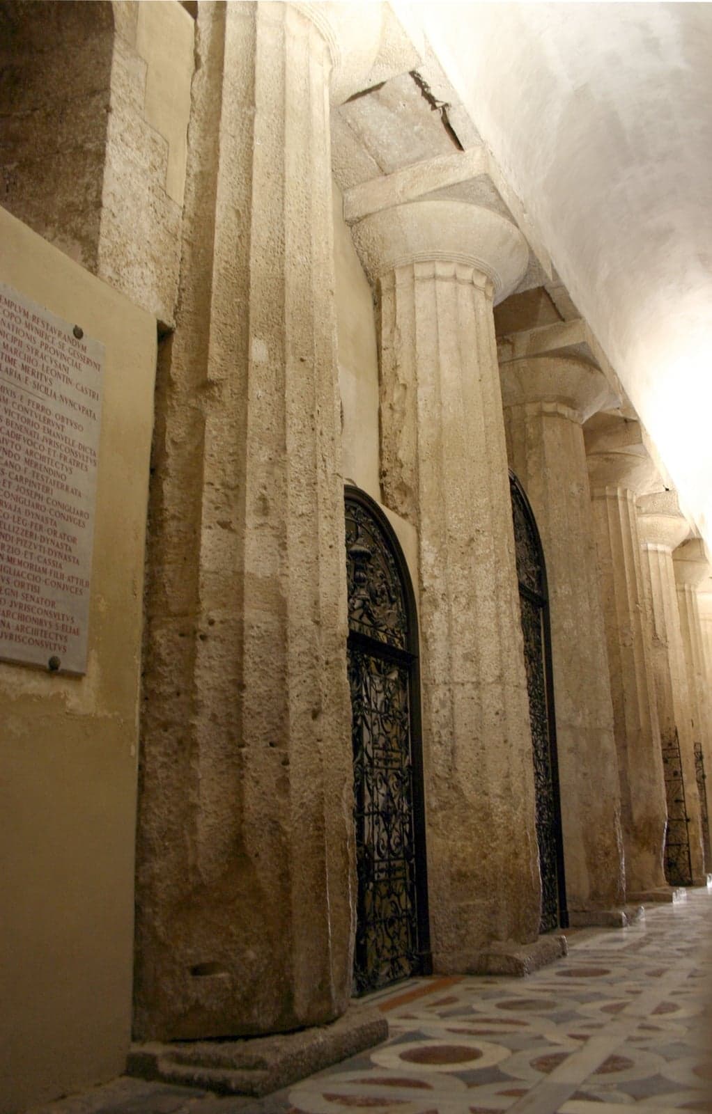 Massive fluted Doric columns from the Temple of Athena built into the wall of the Duomo's right nave, capitals and arches receding down the aisle
