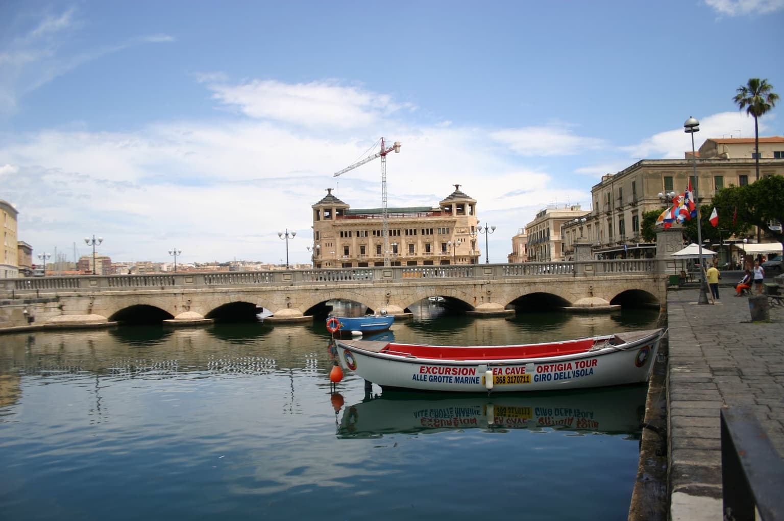 The Ponte Umbertino, the arched bridge linking Ortigia to the mainland, fishing boats moored in the harbor below
