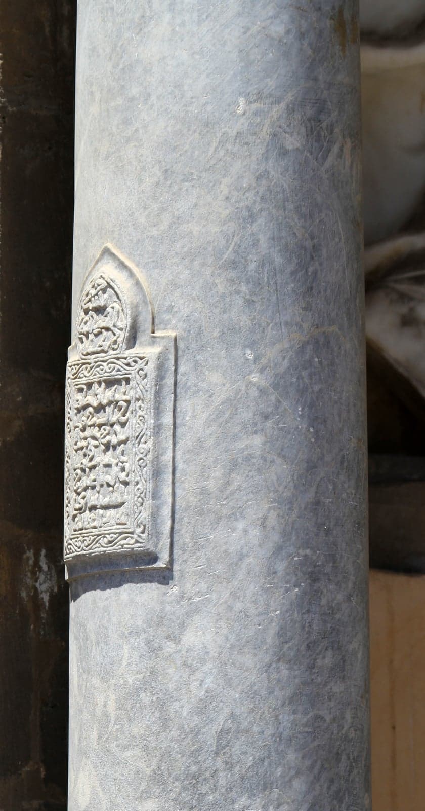 A close view of a carved Arabic inscription set into a column of Palermo Cathedral's porch, the script legible within its decorative border