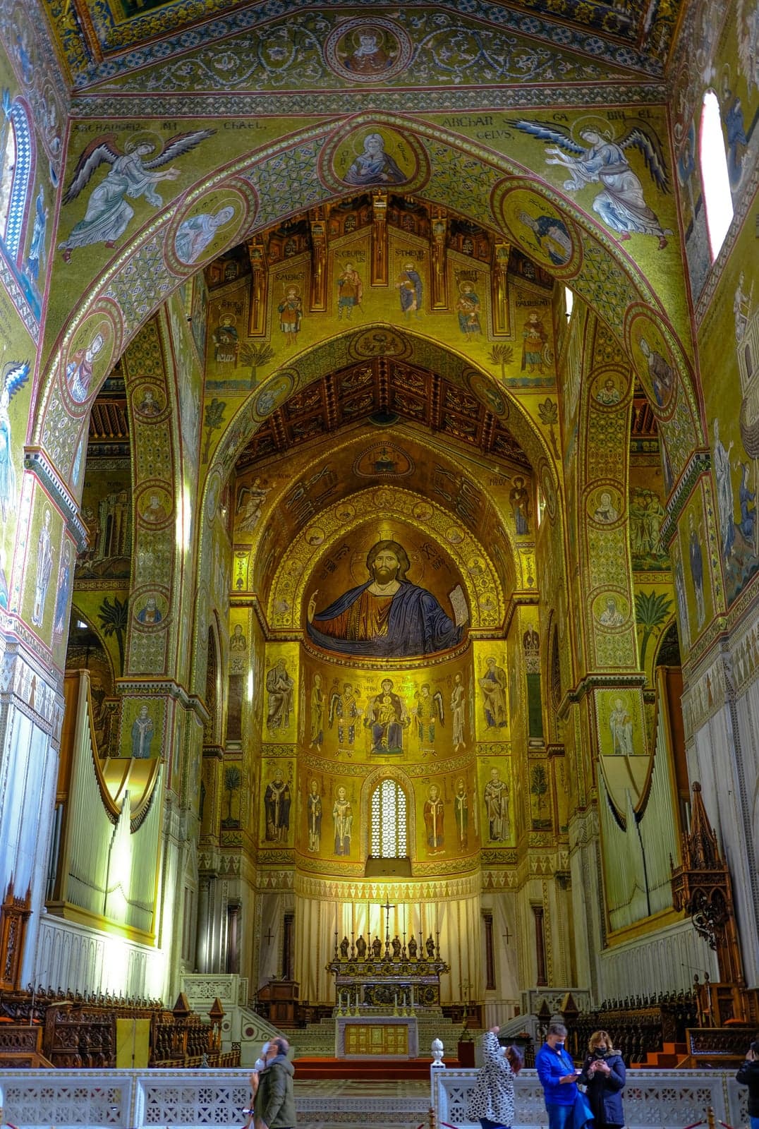 The full apse of Monreale Cathedral, the gold-ground Christ Pantocrator mosaic filling the semi-dome above the enthroned Virgin and rows of saints, dwarfing the surrounding architecture