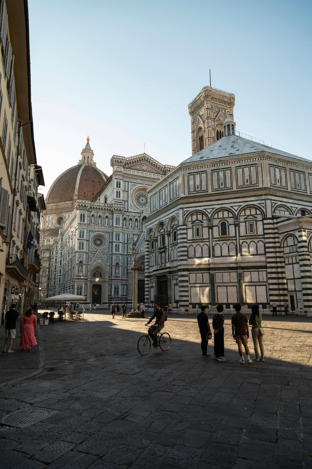 Florence Cathedral's red-brick dome and marble facade, with Giotto's bell tower rising behind the striped octagonal Baptistery in early-morning light