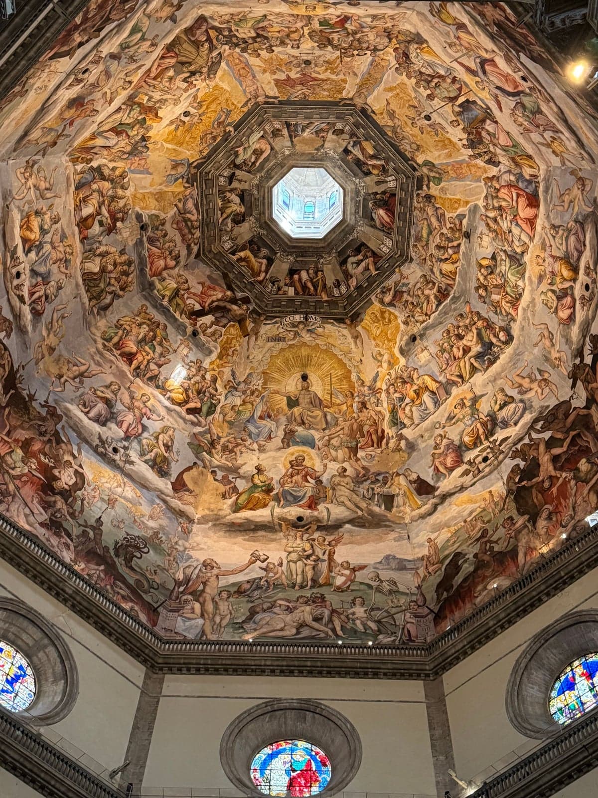Looking straight up into the cathedral dome, every panel of the eight-sided vault painted with crowds of figures rising to a bright opening at the top