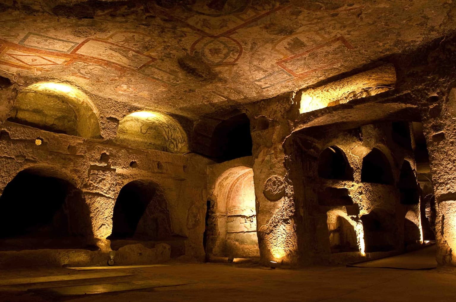 The upper vestibule of the Catacombs of San Gennaro, with a painted ceiling and arched burial niches cut into the tuff