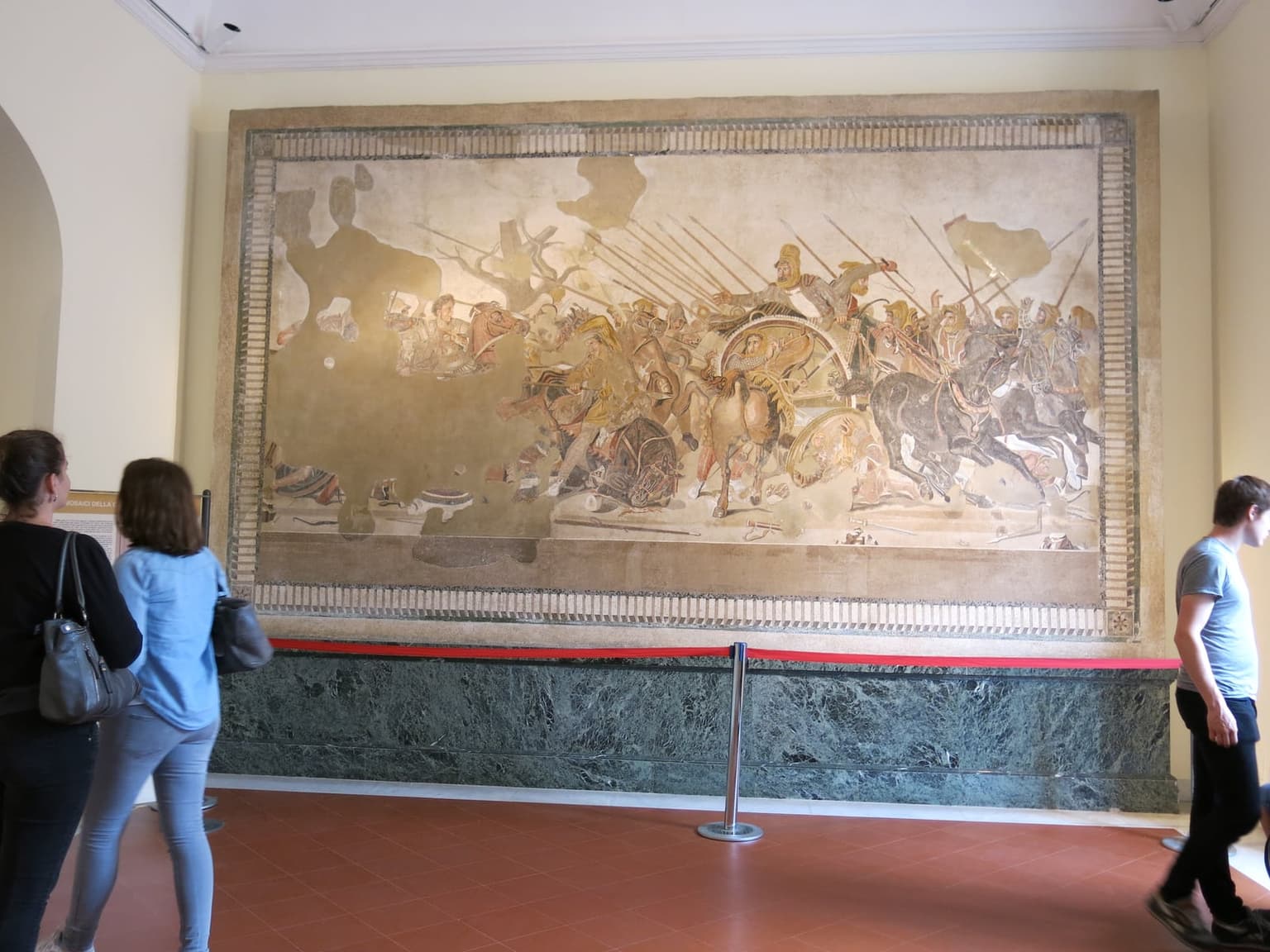 The Alexander Mosaic from Pompeii in its room at MANN, with visitors standing at the rope barrier