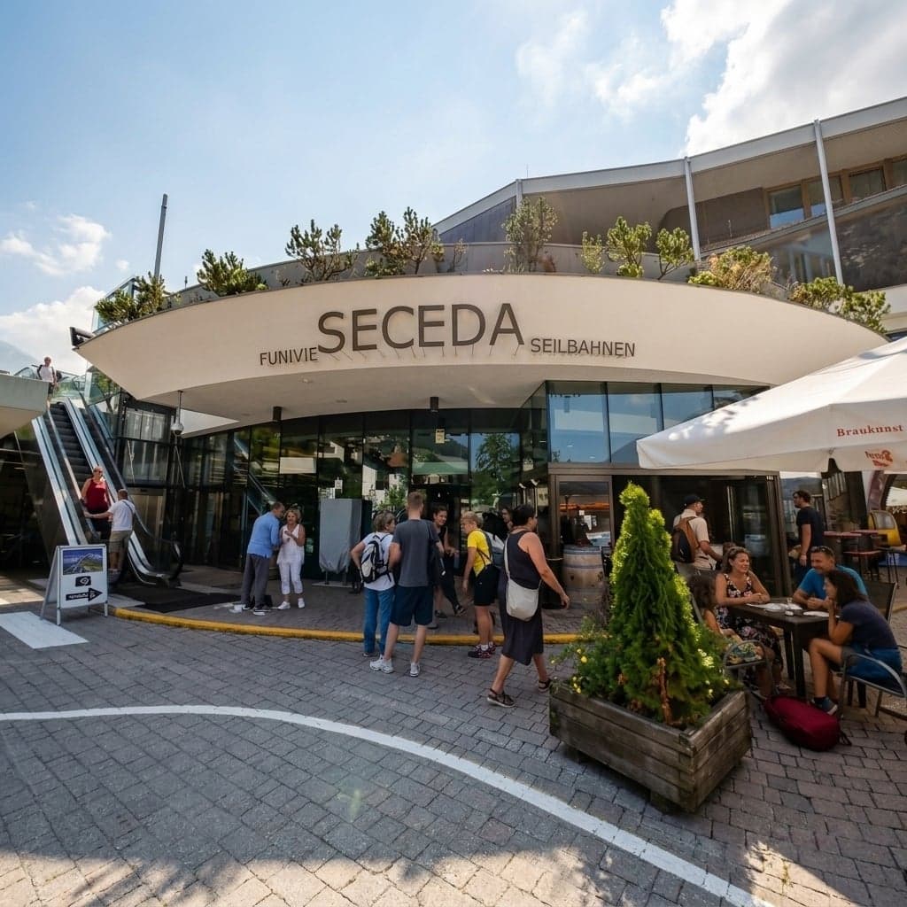 The Seceda cable-car station entrance in Ortisei, with its "Funivie Seceda / Seilbahnen" signage, escalators, and a café terrace, visitors gathered on the paved plaza out front