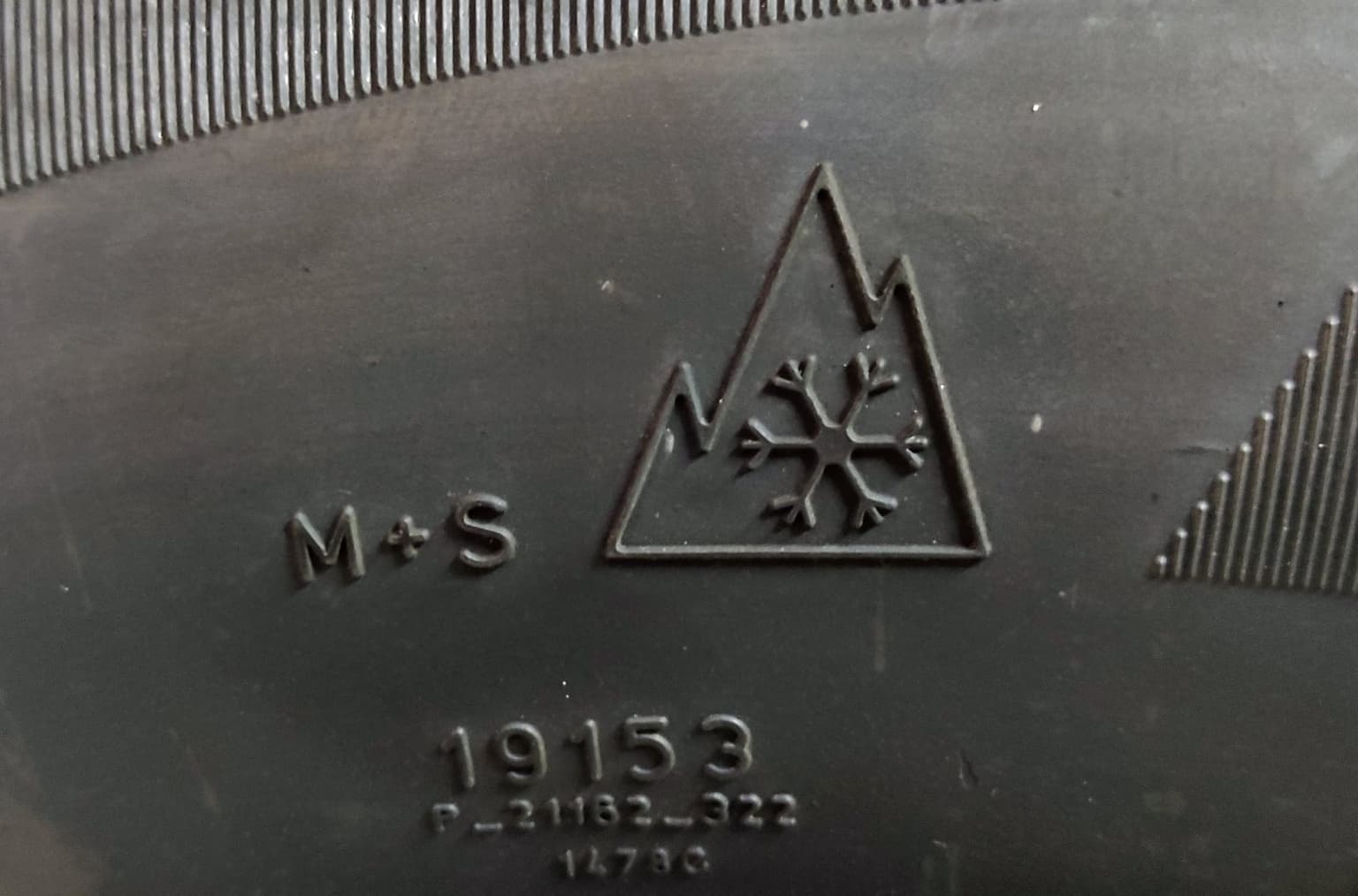 Close-up of a tire sidewall molded with the three-peak mountain-snowflake winter symbol beside the M+S marking