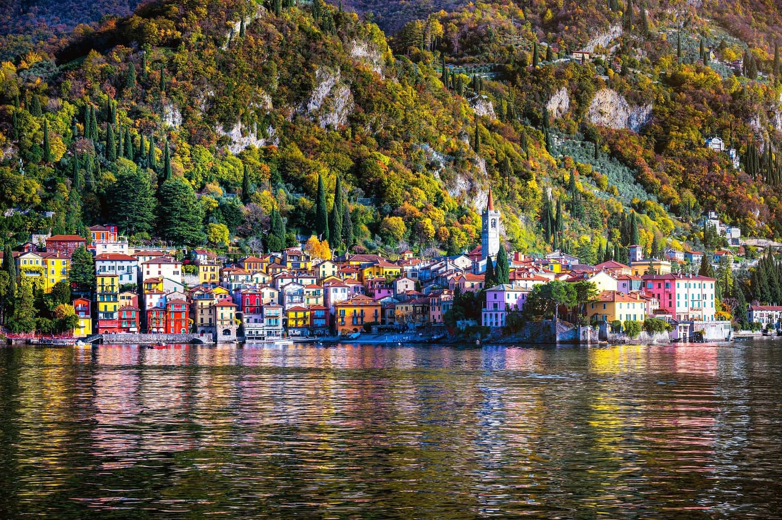 The colorful waterfront of Varenna below autumn foliage, reflected in Lake Como