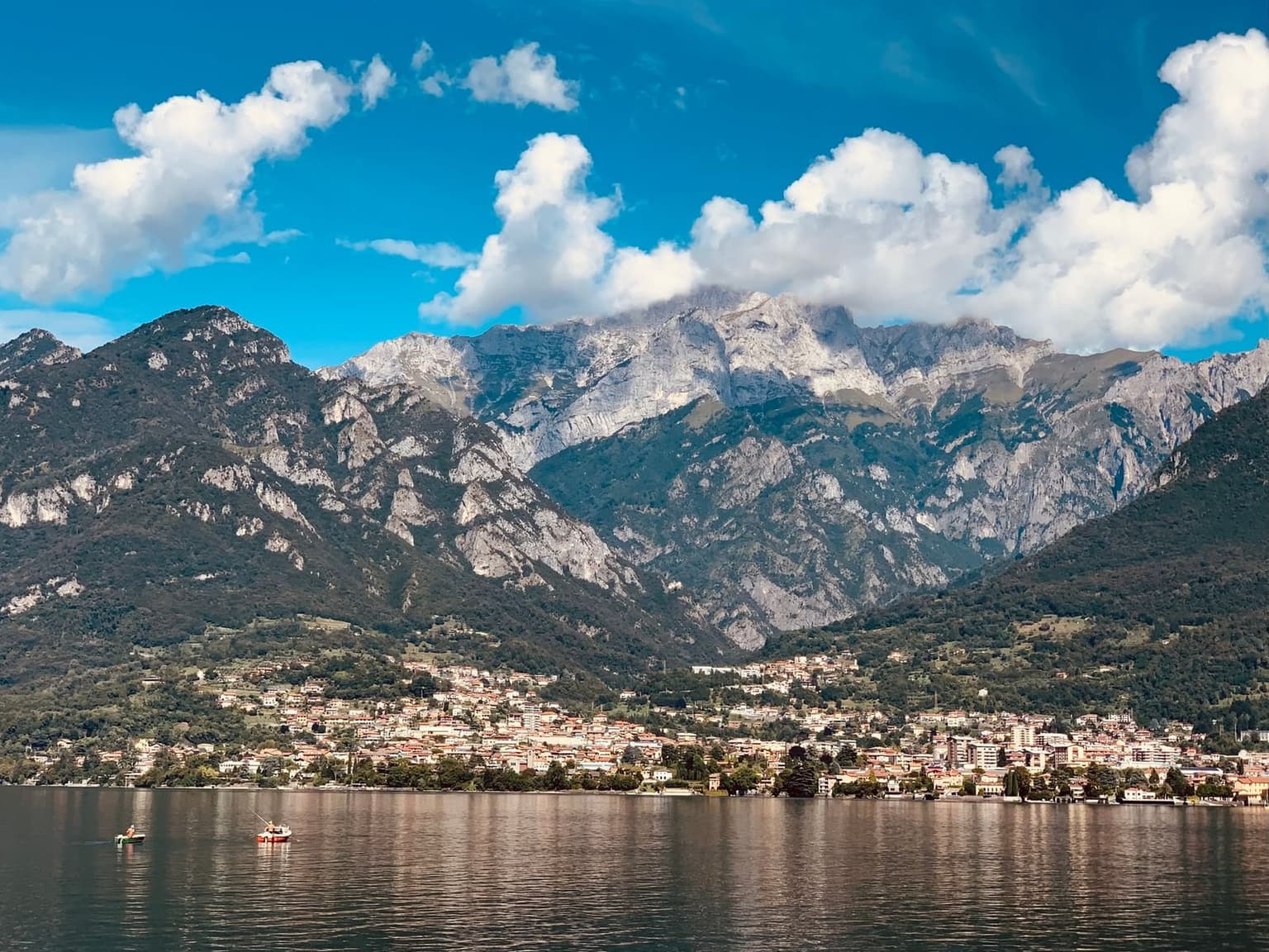 Lake Como ringed by mountains, with small boats out on the water