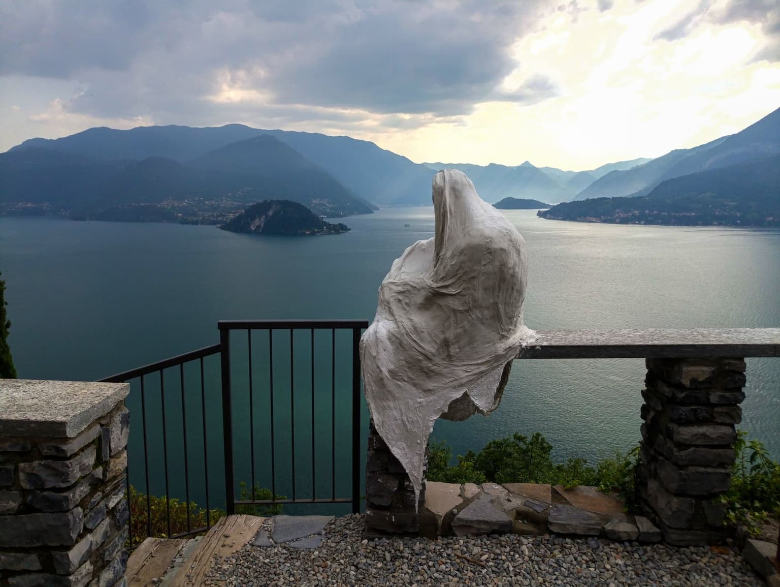 A ghostly plaster figure at Castello di Vezio gazing over the middle of Lake Como toward Bellagio and the mid-lake island