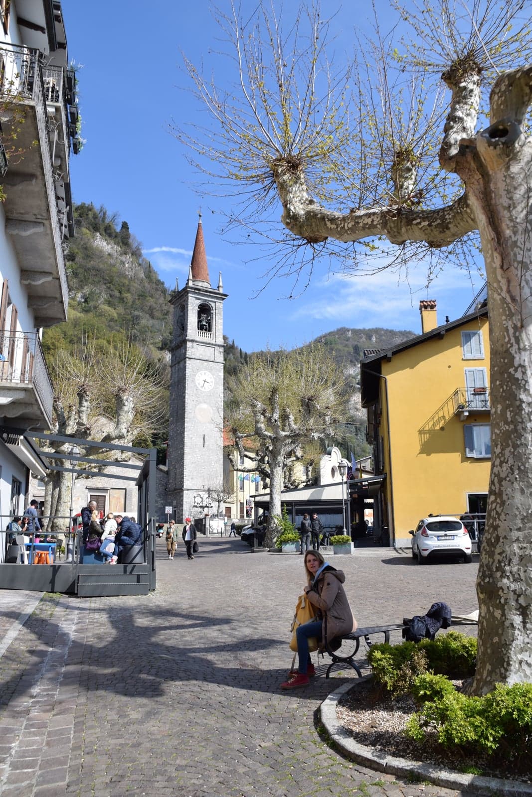 The campanile of the church of San Giorgio rising over Piazza San Giorgio, Varenna's cobbled main square with its pollarded plane trees and colour-washed houses