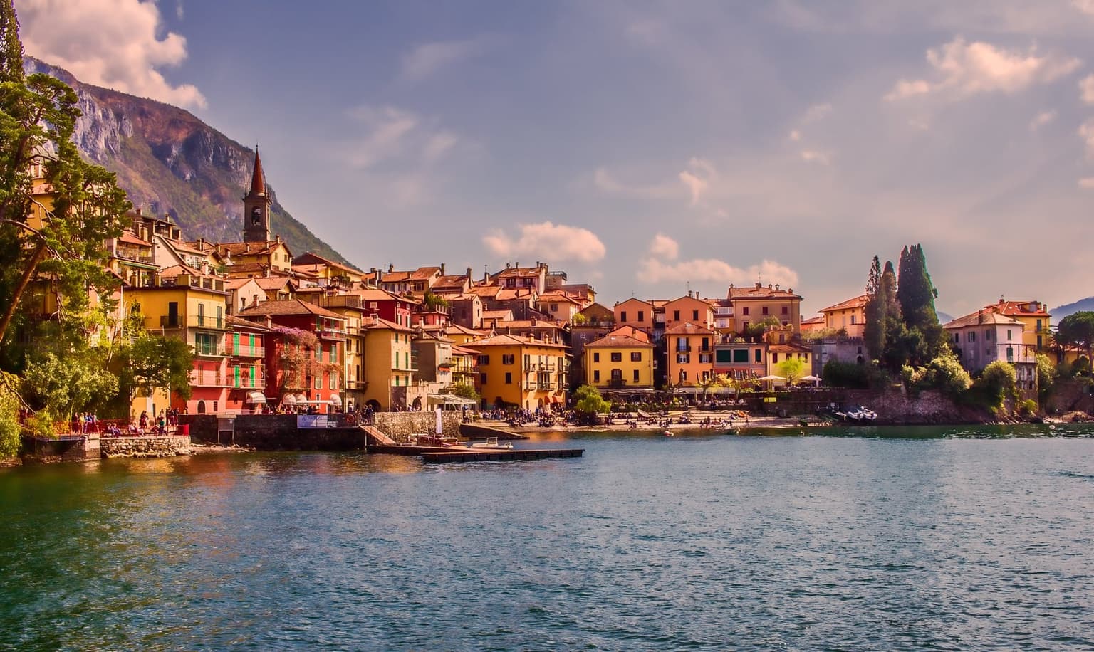 Varenna's pastel houses and church tower stacked up the hillside above the lake at golden hour