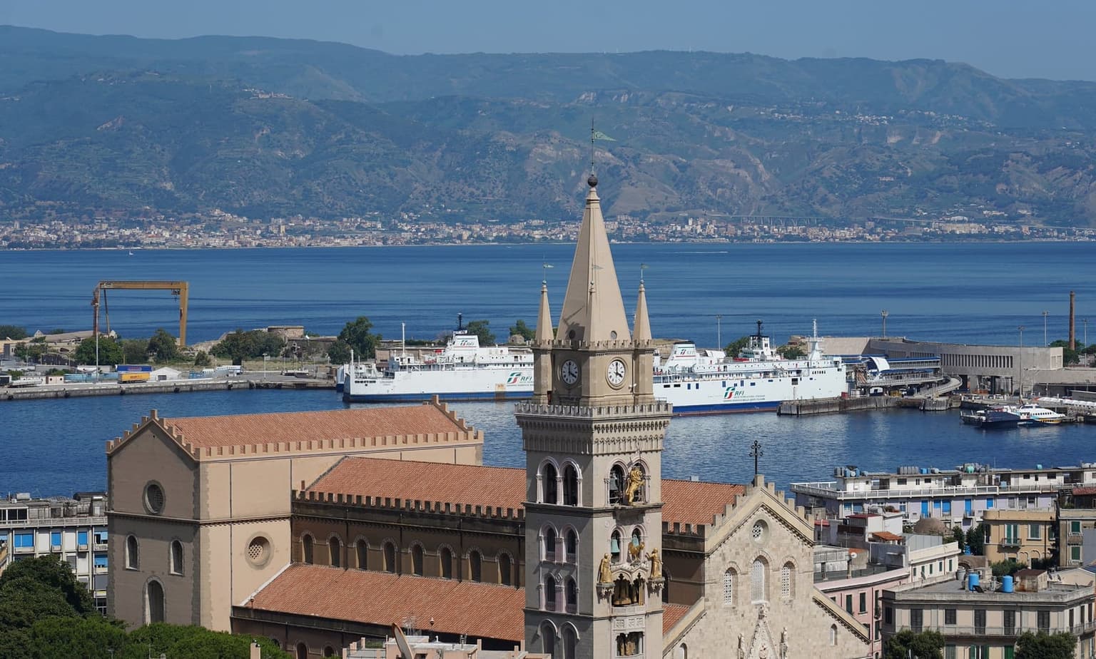 The view from the Montalto belvedere, looking down over Messina's Duomo bell tower and harbor to the Calabrian coast across the strait