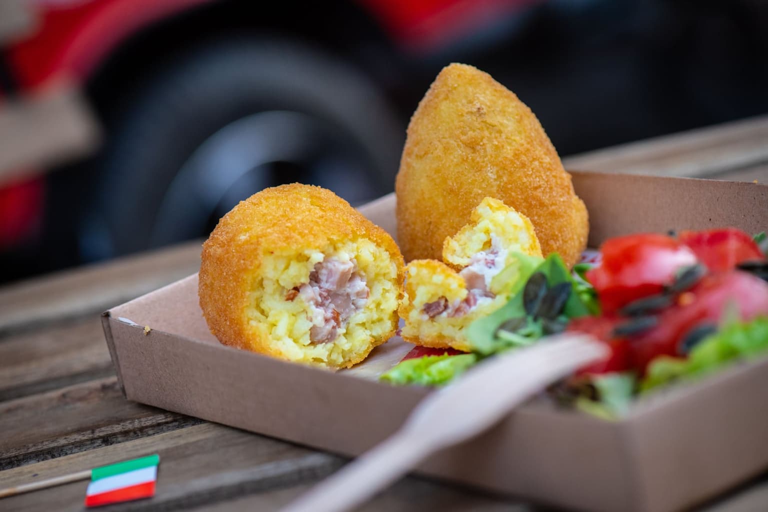 A Catania-style arancino, its pointed cone shape broken open to show the filling