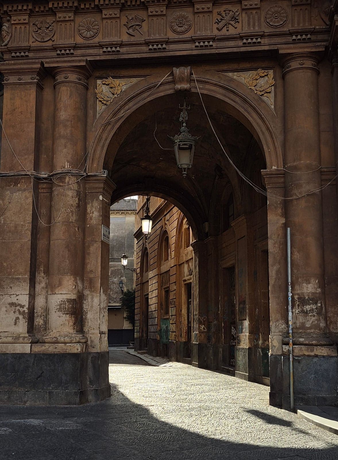 A stone archway in Catania's historic center, the kind La Pescheria market runs beneath on its way to Piazza del Duomo