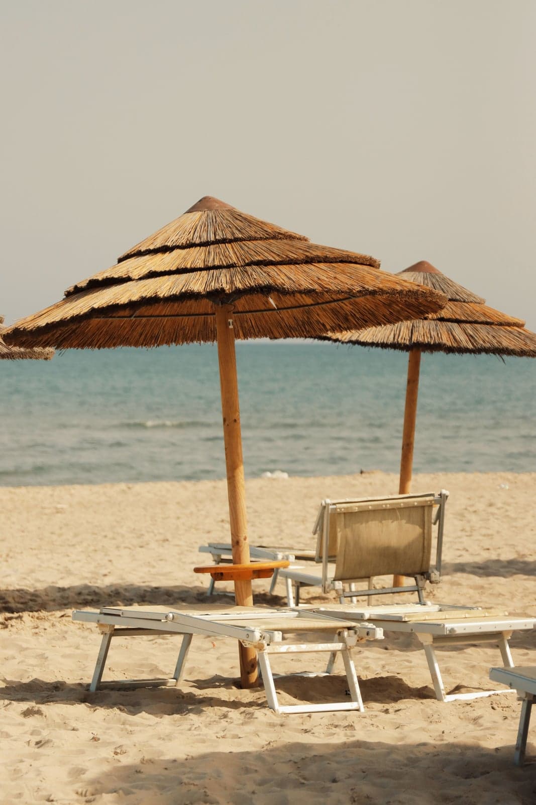 Thatched beach umbrellas and loungers on golden sand, the kind of lido row that lines La Playa in Catania