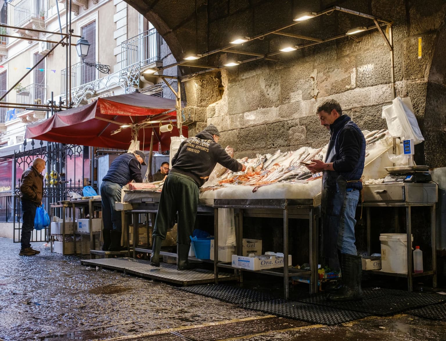 Wet stone counters at La Pescheria fish market in Catania, under the Carlo V wall arch